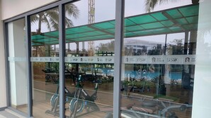 Un gimnasio con equipo de ejercicio, ventanas amplias y un dosel verde.
