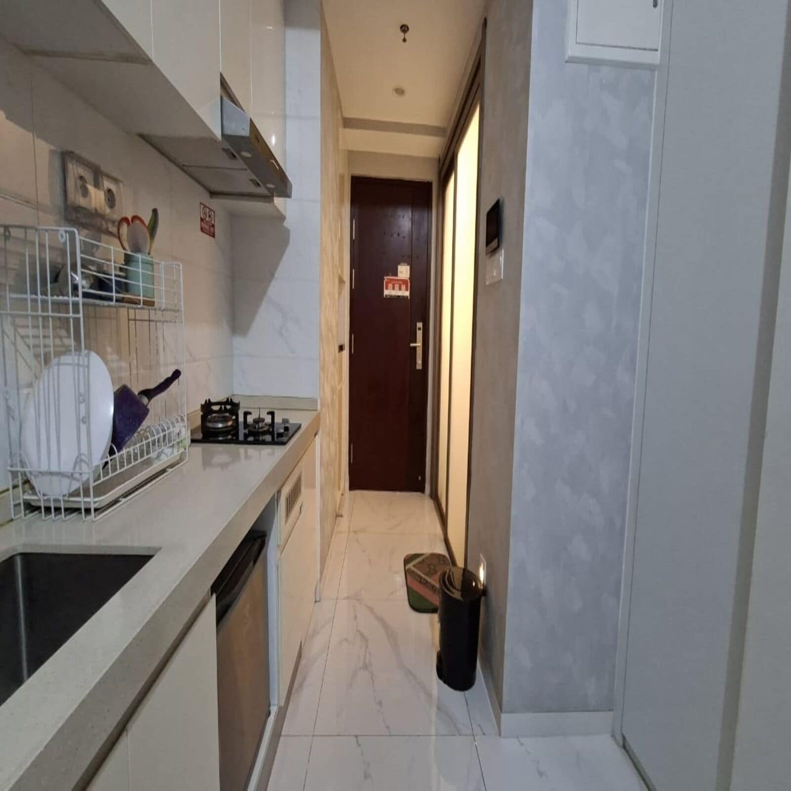 A narrow kitchen with a dishwasher, stove, and a hanging pot rack.
