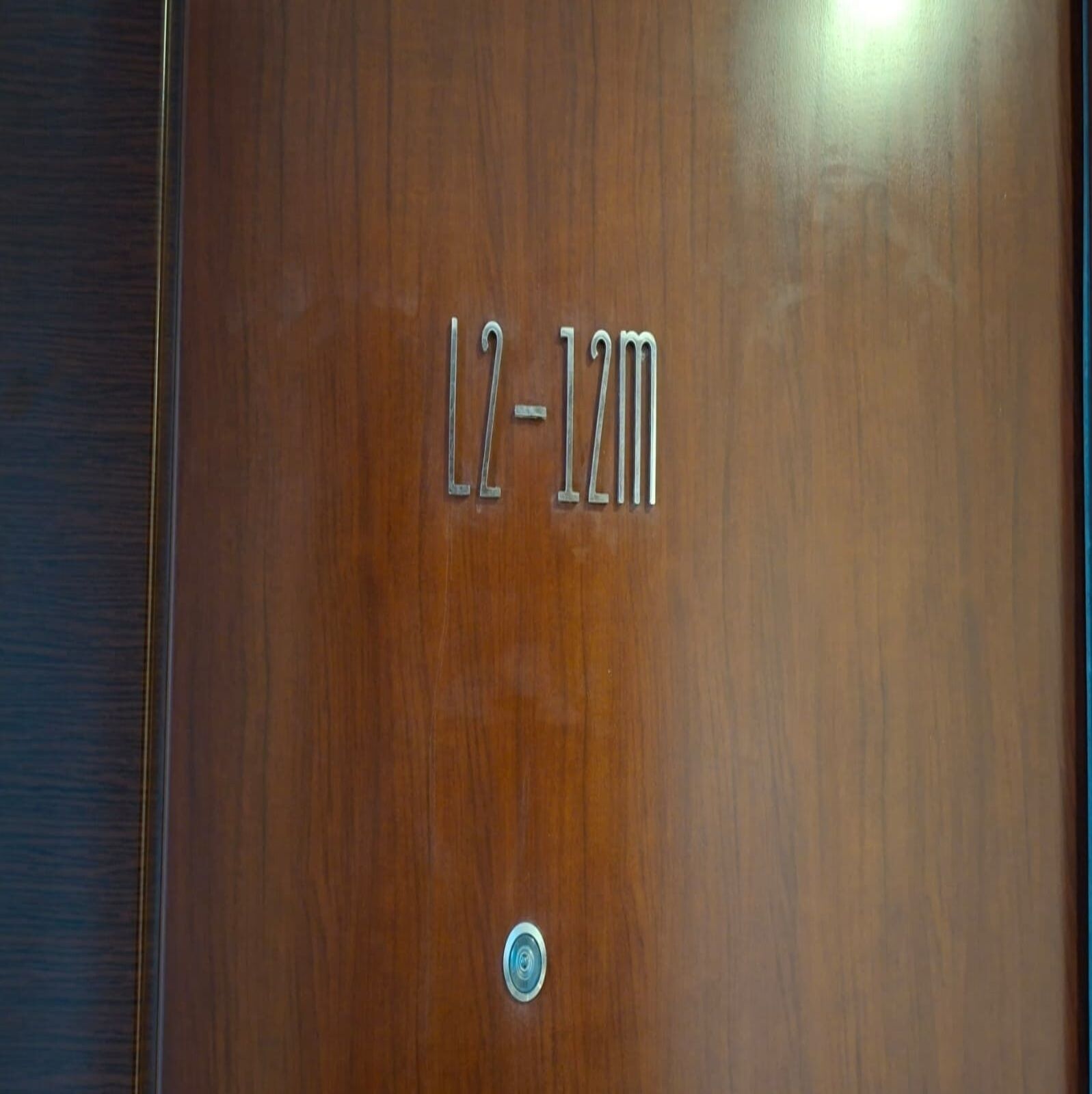 A wooden door with a metal plaque reading "L2-12m".