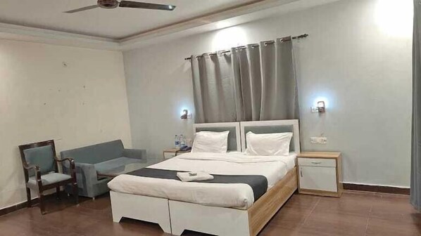 A bedroom with a bed, a chair, a bedside table, and a nightstand. - Shiva solace by Sam Valley (Bhimtal)