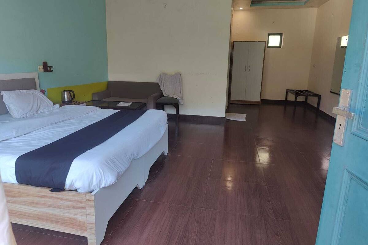 A hotel room with a bed, a sofa, a small table, and a door.