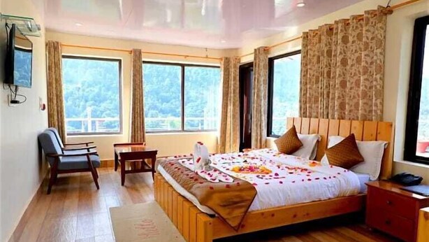 A bedroom with a wooden bed, a desk, a chair, and large windows. - Shiva solace by Sam Valley (Bhimtal)