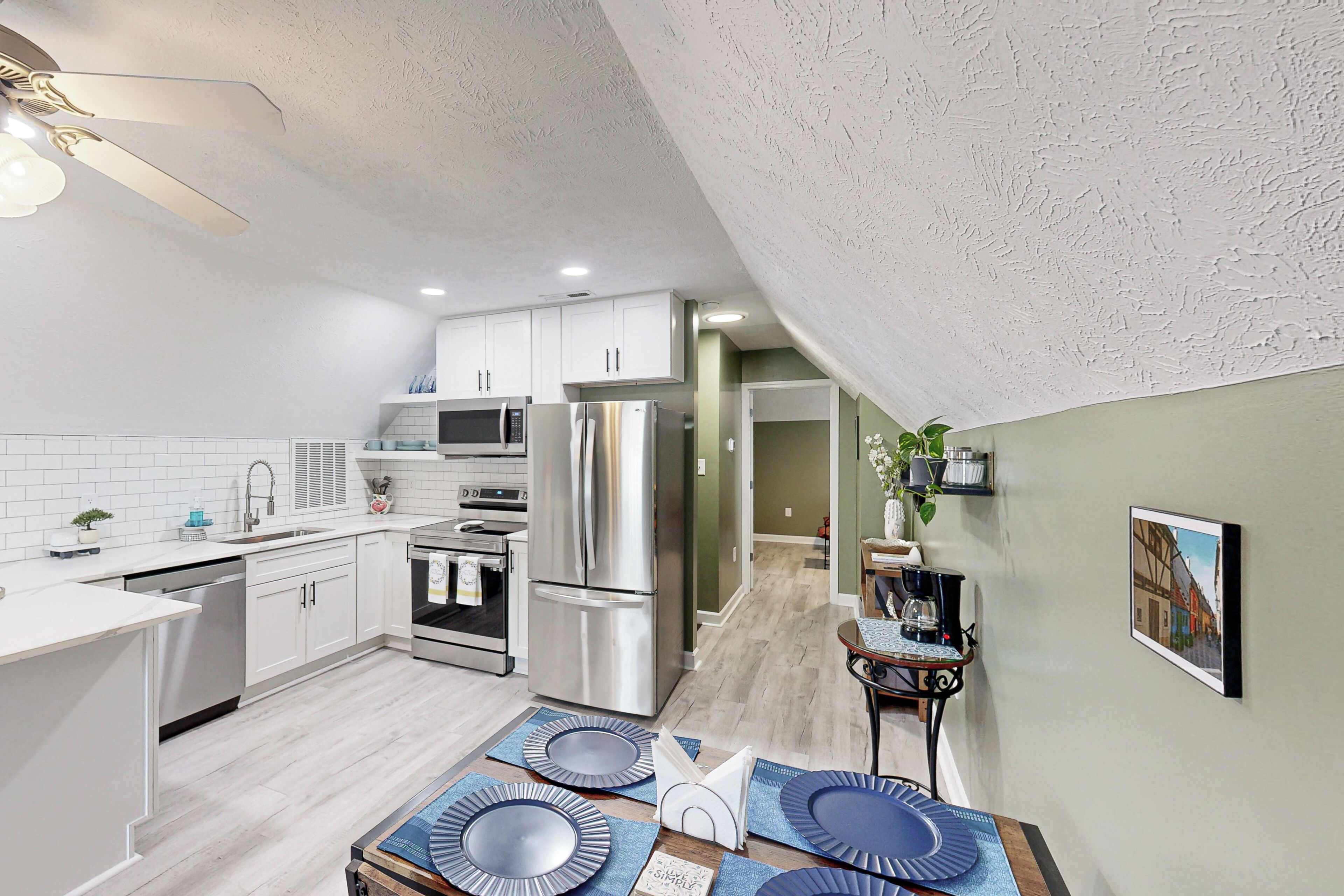 Una cocina moderna con armarios blancos, electrodomésticos de acero inoxidable y una zona de comedor con individuales azules.