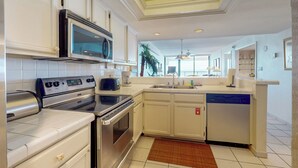 A modern kitchen with stainless steel appliances, white cabinetry, and a central island with a sink. - Shorefront Resort Retreat: Suntide III - Unit 1002 (South Padre Island)