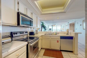 Uma cozinha moderna com eletrodomésticos de aço inoxidável, armários brancos e uma ilha central com pia.