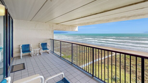 A balcony with a view of the ocean, two chairs, and a small table. - Shorefront Resort Retreat: Suntide III - Unit 1002 (South Padre Island)