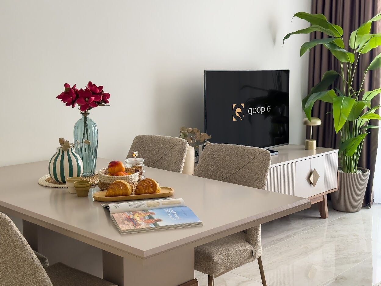 A modern dining area with a table set for a meal, a television, and a potted plant.