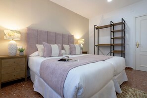 Quarto bem arrumado com cama, mesas de cabeceira, abajur, escada e porta.