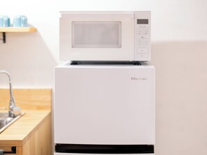 Ein weißer Hisense Kühlschrank mit digitaler Anzeige, einem Gefrierfach und einer Mikrowelle darüber.