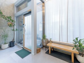Ein modernes Interieur mit Glastür zu einem Balkon, einer Holzbank und Topfpflanzen.