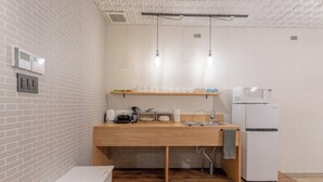 Cocina compacta con encimera de madera, pileta, microondas y heladera. Hay luces colgantes y un revestimiento de pared con diseño de ladrillo.