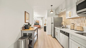 Een moderne keuken met witte kasten, roestvrijstalen apparatuur en een houten aanrecht.