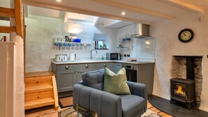 Un espacio habitable compacto con kitchenette, chimenea y una zona de estar acogedora.
