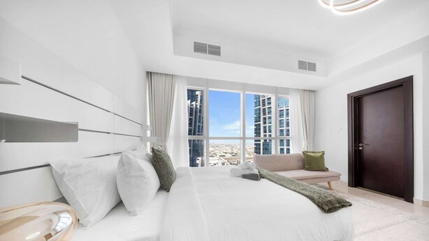 Ein modernes Hotelzimmer mit einem großen Bett, einer Couch und Blick auf die Stadt.
