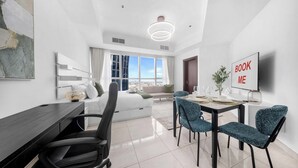 Ein modernes Hotelzimmer mit Bett, Schreibtisch, Essbereich und einem großen Fenster mit Blick auf die Stadt.