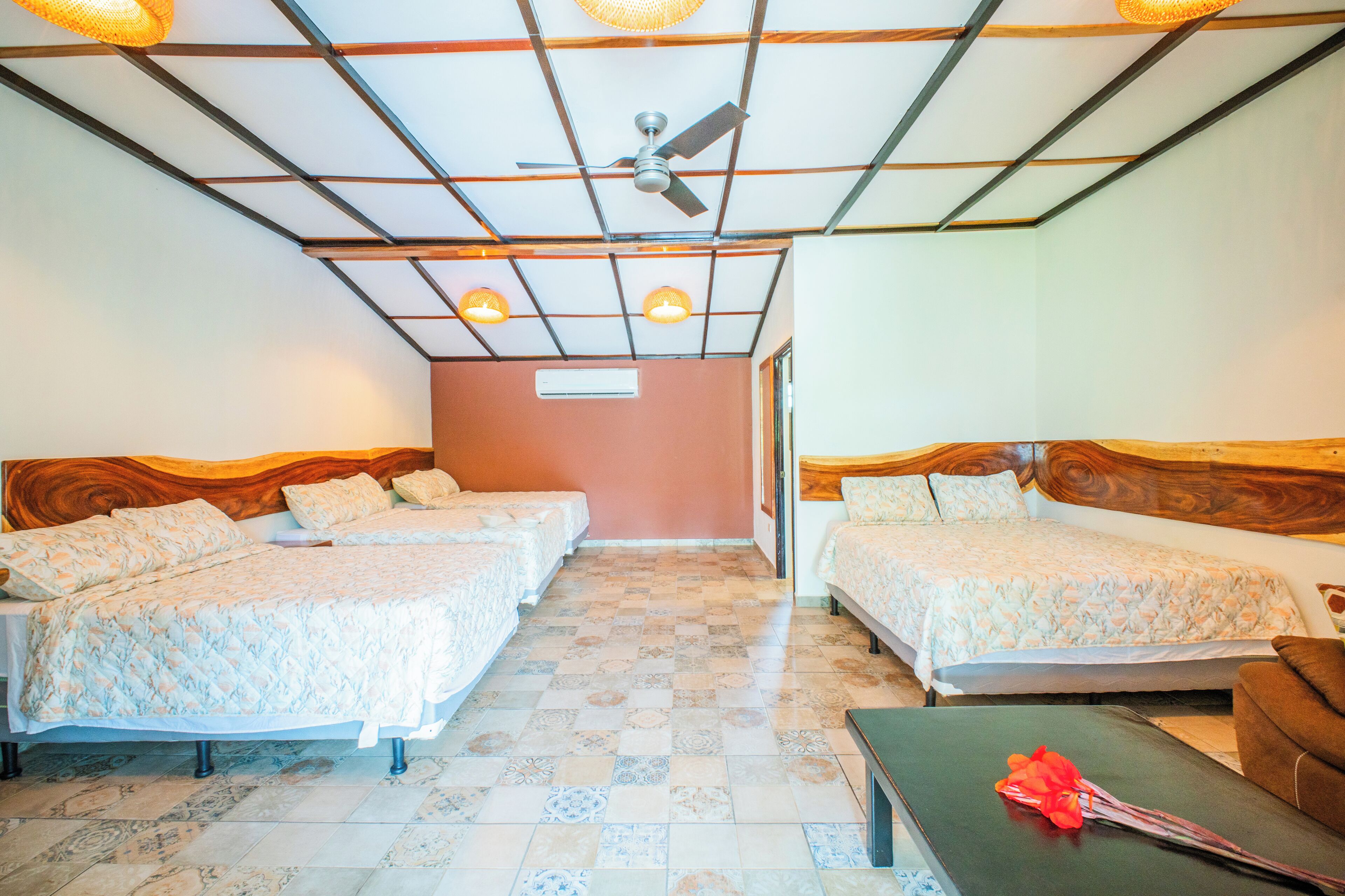 A hotel room with two beds, a ceiling fan, and a small table with a red object on it.