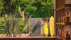 A room with a stone wall, a surfboard, and a shelf with bottles. - Casa Las Flores (El Cuco)