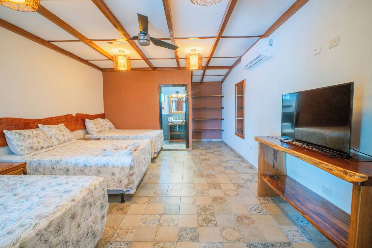 Habitación de hotel con dos camas, televisi ón, vigas de madera en el techo y suelo de baldosas.
