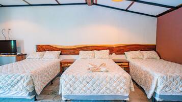 A room with two beds, a wooden headboard, a television on a stand, and patterned floor tiles.