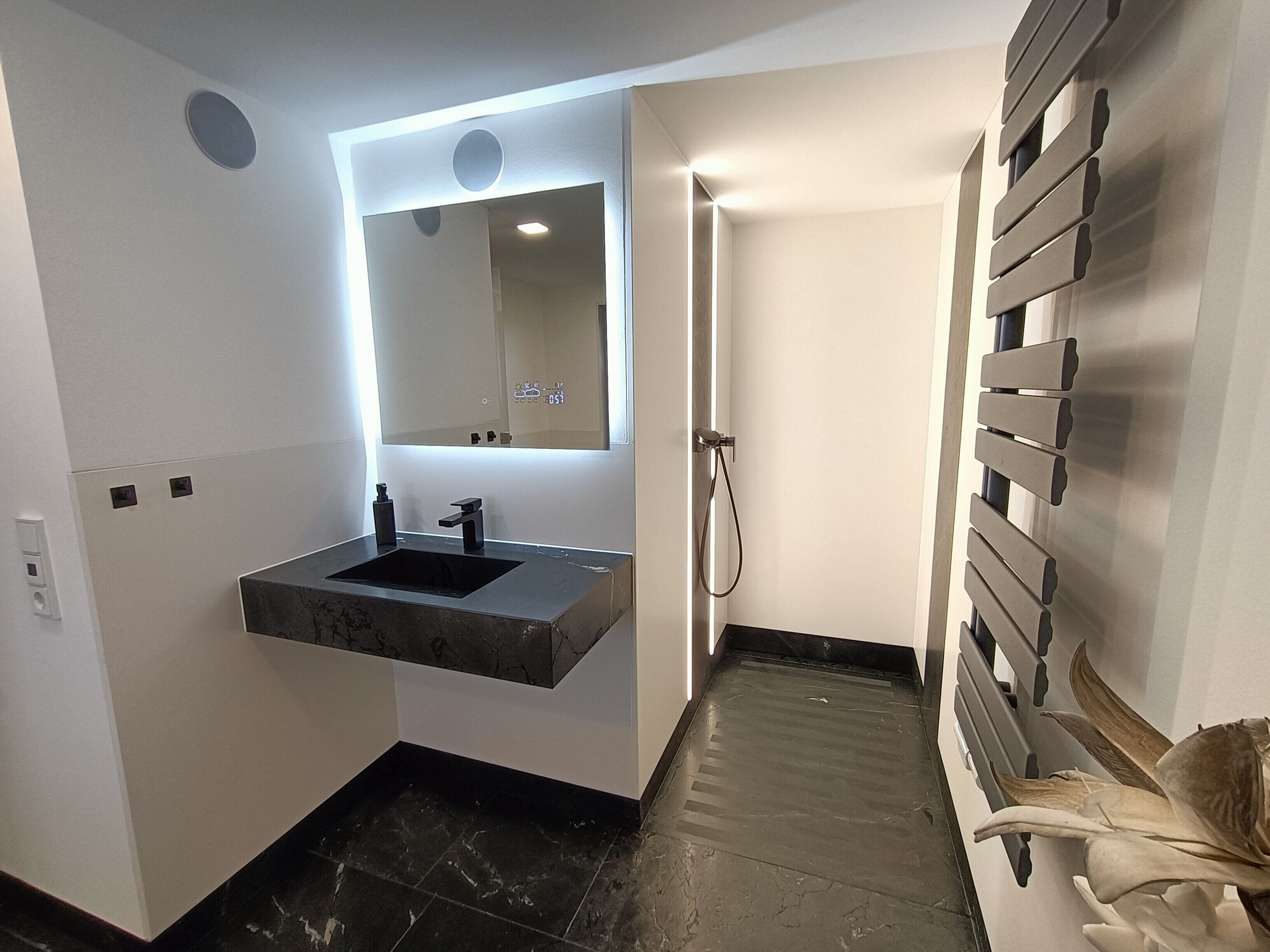 A modern bathroom with a built-in sink, a mirror, and a shower area.