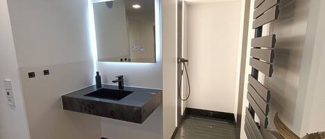 A modern bathroom with a built-in sink, a mirror, and a shower area.