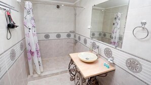 A bathroom with a shower, a sink with a mirror, and decorative tiles.