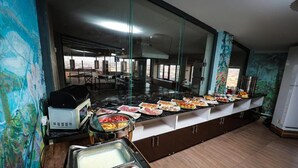 A buffet area with various food items, a coffee machine, and a milk dispenser.