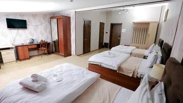 Una habitación de hotel con cama, escritorio, silla, televisor y espejo.