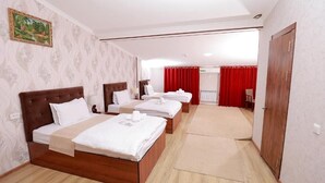 A hotel room with three wooden beds, a large mirror, and a red curtain.