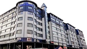 A multi-story hotel with a modern architectural design, featuring a prominent corner tower and a series of balconies.