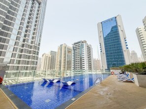 A rooftop pool with clear blue water, surrounded by high-rise buildings.