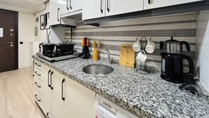 A kitchen with white cabinets, a granite countertop, a stove, a sink, and various utensils. - One-Bedroom Apartment in Taksim - No: 11 (Beyoglu)