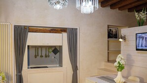 A compact kitchen with a built-in sink, wooden cabinets, and a dining area with a table and chairs. - Casa Pannella (Vittorio Veneto)