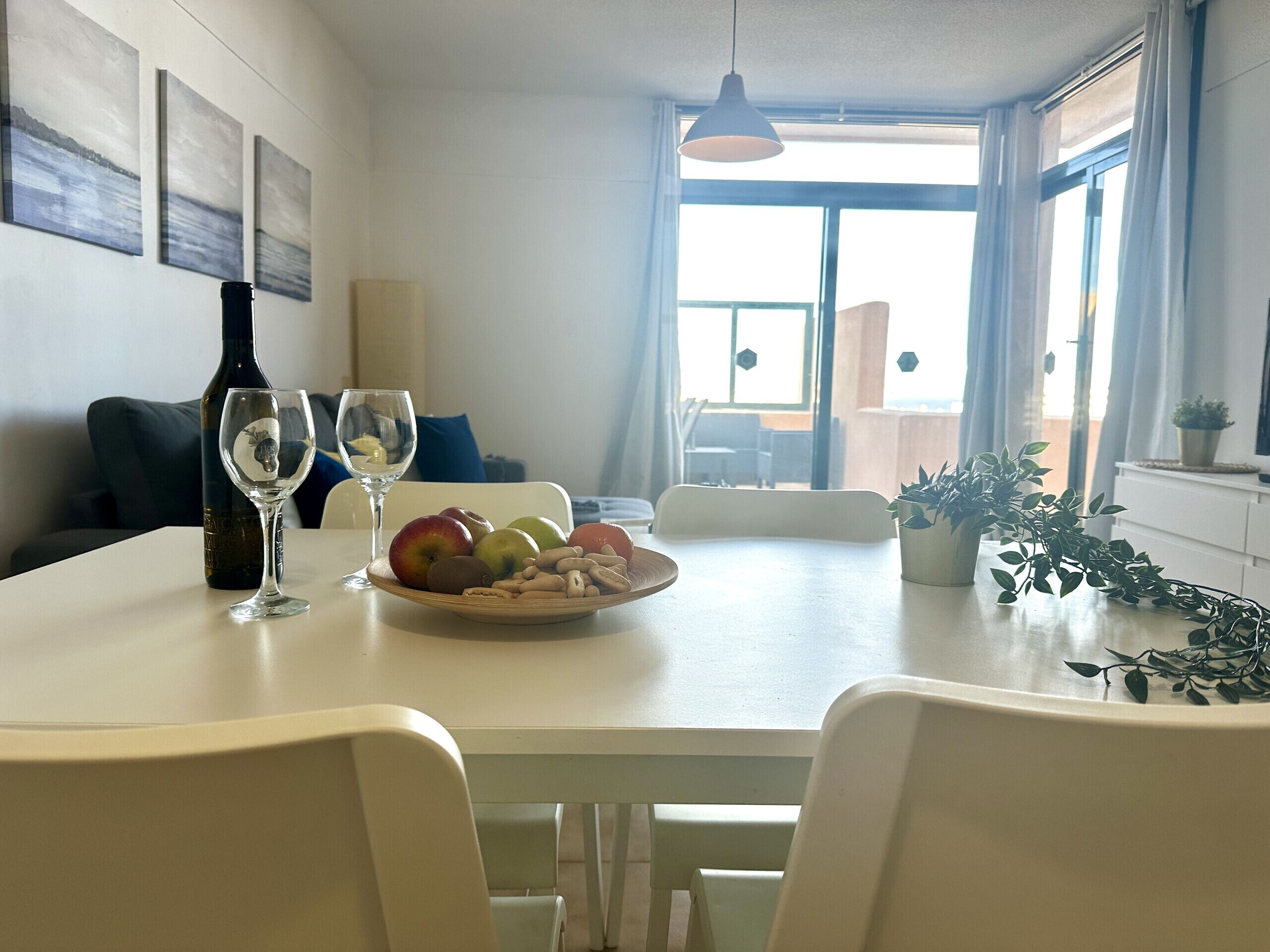 Comedor con mesa dispuesta para dos, una botella de vino y un frutero.