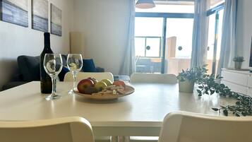 Comedor con mesa dispuesta para dos, una botella de vino y un frutero.