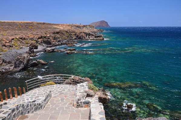 Une vue sur la côte, avec un escalier en pierre menant à un rivage rocheux.