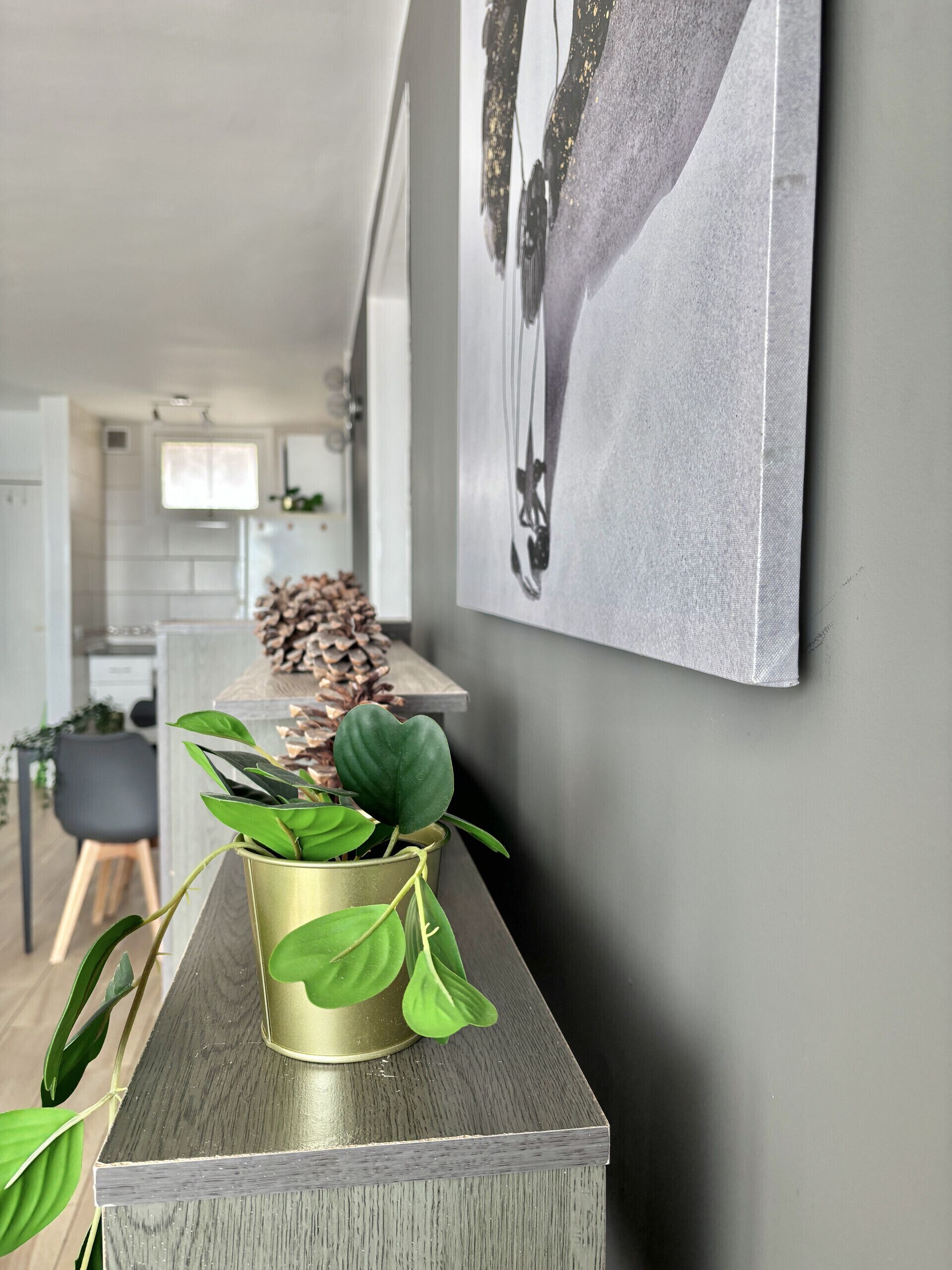 Une cuisine moderne avec un plan de travail en bois, une plante en pot et une œuvre d’art accrochée au mur.