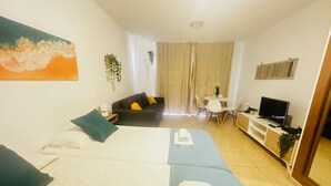 A hotel room with a bed, a sofa, a TV, and a dining area. - LA BELLA CAROLINA EN COSTA DEL SILENCIO (Costa del Silencio)