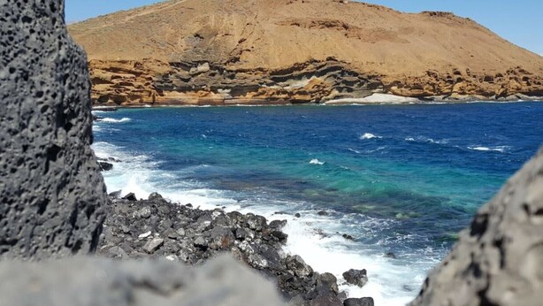 A rocky coastline with clear blue waters and a mountain in the background. - LA BELLA CAROLINA EN COSTA DEL SILENCIO (Costa del Silencio)