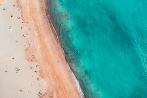 Vista aérea de uma praia com águas turquesa cristalinas e uma faixa de areia.
