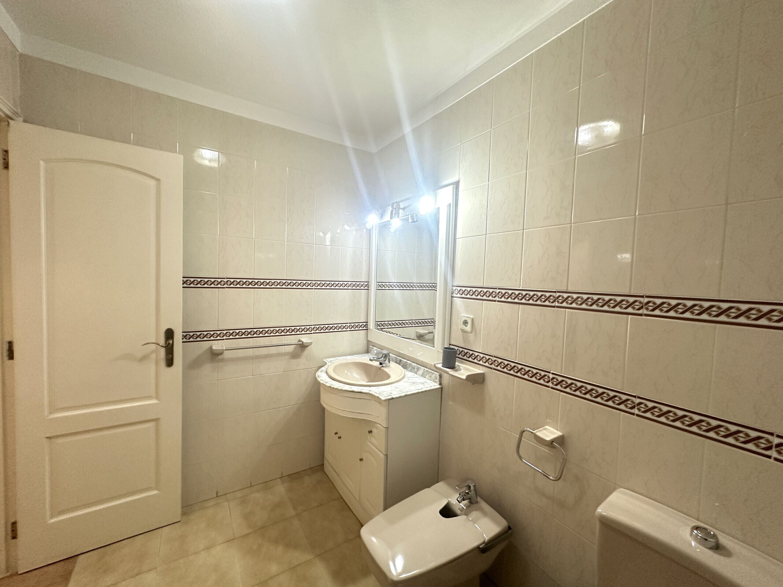 Un baño con inodoro, lavamanos y espejo.