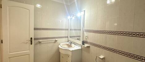 Un baño con inodoro, lavamanos y espejo.