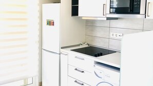 Cocina compacta con microondas integrado, refrigerador, estufa y lavadora.