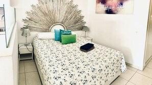 Un dormitorio con cama, almohadas, una obra de arte en la pared y una mesita de noche.