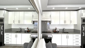 A modern kitchen with white cabinets, granite countertops, stainless steel appliances, and a built-in oven.