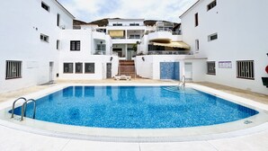 A swimming pool surrounded by white buildings with balconies and windows.