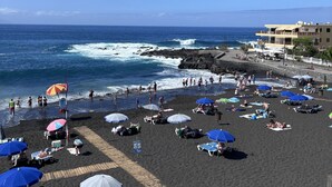A beach with people sunbathing and swimming, umbrellas, and a rocky shoreline. - Coastal Retreats Beach & Ocean View Playa Arena (Santiago del Teide)
