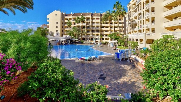 A hotel with a swimming pool surrounded by lush greenery and palm trees. - Sunny Views Los Cristianos (Los Cristianos)