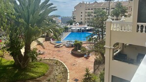 A resort with a swimming pool surrounded by palm trees and lounge chairs. - Sunny Views Los Cristianos (Los Cristianos)