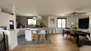 A modern kitchen with white cabinets, a central island with stools, and a dining area with a table and chairs. - HOUSE LE CLOS JOLY NEAR TRAIN STATION 3 BEDROOMS (Les Sables-d'Olonne)